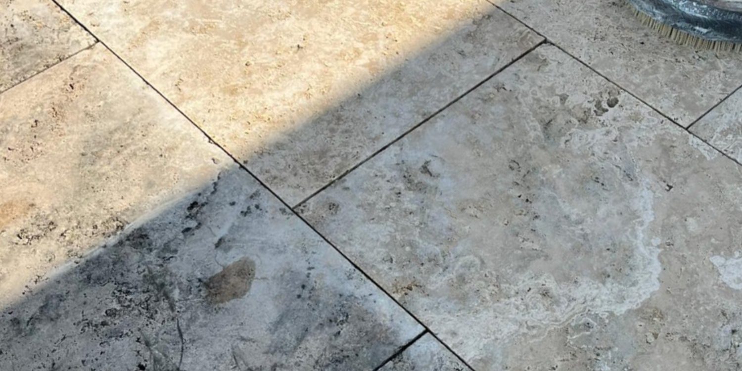Travertinplatten im Außenbereich mit Schmutz und Flecken, die durch falsche Pflege oder ungeeignete Reinigungsmethoden entstanden sind.