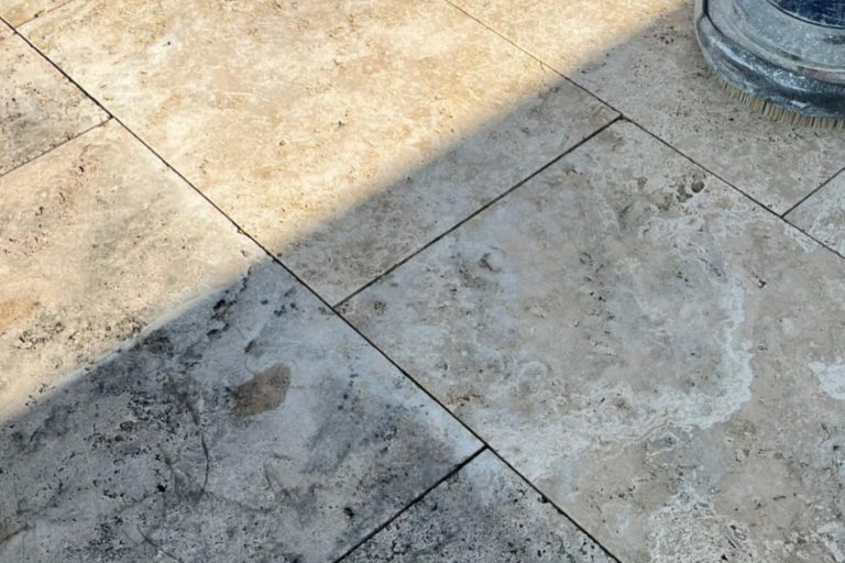 Travertinplatten im Außenbereich mit Schmutz und Flecken, die durch falsche Pflege oder ungeeignete Reinigungsmethoden entstanden sind.